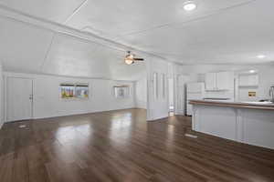 Unfurnished living room with ceiling fan, dark wood-type flooring, and lofted ceiling