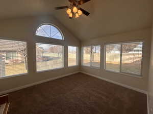 Unfurnished sunroom with ceiling fan and vaulted ceiling