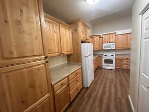 Kitchen featuring a textured ceiling, dark hardwood / wood-style flooring, and white appliances