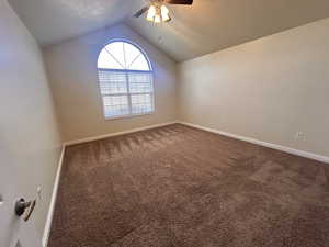 Carpeted spare room featuring ceiling fan and lofted ceiling