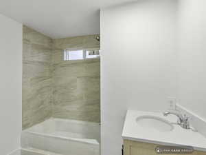 Bathroom featuring vanity and tiled shower / bath