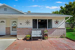 Doorway to property featuring covered porch and a patio