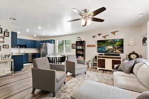 Living room with ceiling fan, light hardwood / wood-style flooring, and sink