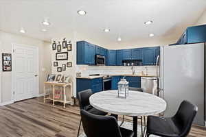 Kitchen featuring backsplash, sink, hardwood / wood-style flooring, blue cabinetry, and appliances with stainless steel finishes