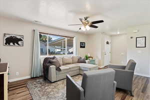 Living room with hardwood / wood-style flooring, ceiling fan, and a textured ceiling