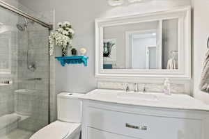 Bathroom with vanity, a shower with shower door, and toilet