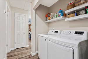 Laundry room featuring washing machine and dryer and light hardwood / wood-style flooring