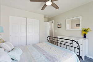 Carpeted bedroom with ceiling fan and a closet