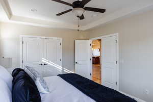 Bedroom featuring ceiling fan, a raised ceiling, and a closet