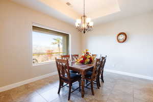 Dining area featuring a tray ceiling, tile patterned floors, and an inviting chandelier