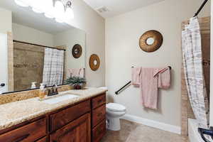 Full bathroom with tile patterned floors, vanity, shower / tub combo, and toilet