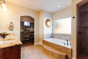 Bathroom featuring tile patterned floors, vanity, and shower with separate bathtub