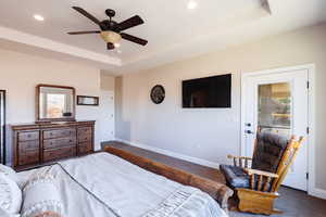 Carpeted bedroom featuring ceiling fan and a raised ceiling