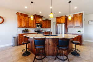 Kitchen with a kitchen breakfast bar, stainless steel appliances, and an island with sink