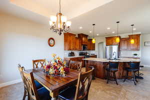 Dining room with a tray ceiling, sink, and a notable chandelier