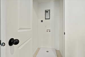 Laundry area with hookup for an electric dryer, light tile patterned flooring, and washer hookup