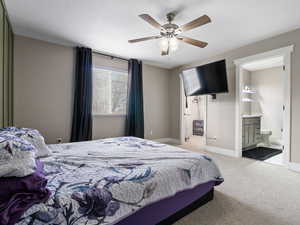 Carpeted bedroom featuring ceiling fan and connected bathroom