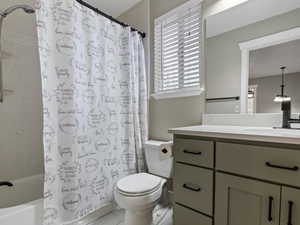 Full bathroom with vanity, toilet, and shower / bath combo with shower curtain