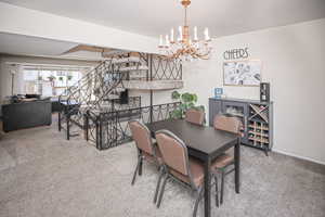 Dining area with carpet flooring and a notable chandelier