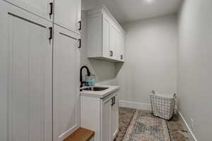 Clothes washing area featuring brick floor, a sink, and baseboards