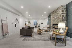 Living room with baseboards, a stone fireplace, light colored carpet, and recessed lighting