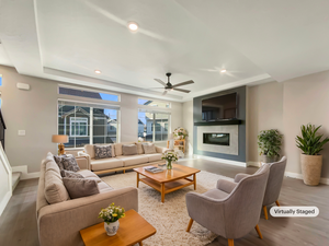 Living room featuring a raised ceiling, ceiling fan, and light wood-type flooring