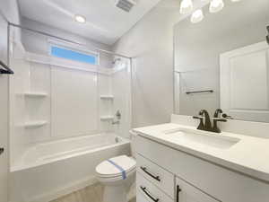 Full bathroom featuring hardwood / wood-style flooring, toilet, vanity, and washtub / shower combination