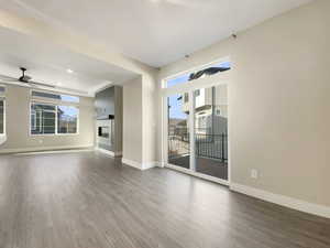 Unfurnished living room with hardwood / wood-style flooring, ceiling fan, and plenty of natural light