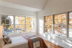 Bedroom with hardwood / wood-style floors and lofted ceiling