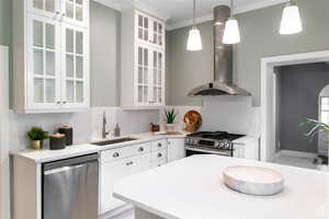 Kitchen featuring island exhaust hood, stainless steel appliances, sink, pendant lighting, and white cabinets