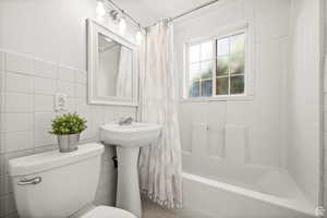 ADU -Bathroom featuring shower / bath combination with curtain, toilet, and tile walls