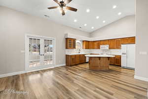 Kitchen featuring ceiling fan, french doors, high vaulted ceiling, white appliances, and a kitchen island