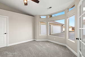 Carpeted empty room featuring ceiling fan and lofted ceiling