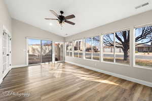 Unfurnished sunroom with ceiling fan and vaulted ceiling