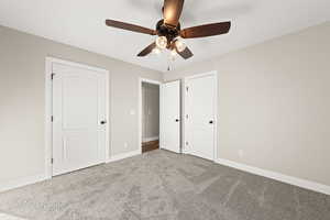 Unfurnished bedroom featuring ceiling fan and light colored carpet