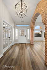 Foyer entrance with a notable chandelier, wood-type flooring, and french doors