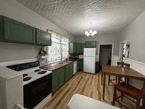 Kitchen with green cabinets, sink, and white appliances