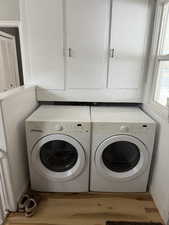 Laundry room featuring cabinets, independent washer and dryer, and light wood-type flooring