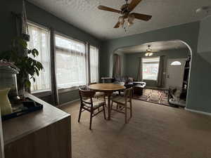 Carpeted dining room featuring a textured ceiling and ceiling fan