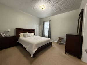 Carpeted bedroom featuring a textured ceiling