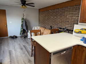 Kitchen featuring ceiling fan, dishwasher, light hardwood / wood-style flooring, brick wall, and a textured ceiling