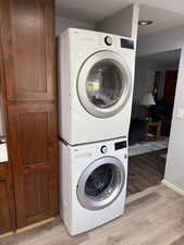 Laundry area with stacked washer and dryer and light hardwood / wood-style floors