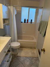 Full bathroom with tile patterned flooring, vanity, shower / bath combo, and toilet