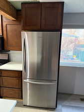 Kitchen with stainless steel fridge, stove, and a textured ceiling