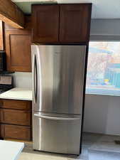 Kitchen with range and stainless steel refrigerator