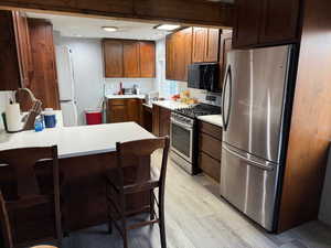 Kitchen featuring a breakfast bar area, light wood-type flooring, and appliances with stainless steel finishes