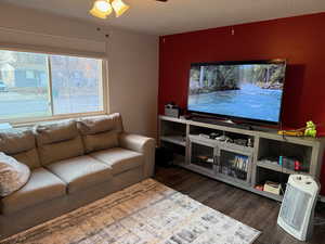 Living room with ceiling fan, dark hardwood / wood-style flooring, and a textured ceiling