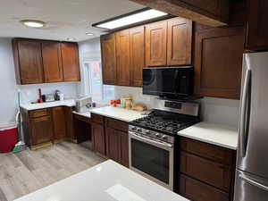 Kitchen with light hardwood / wood-style floors and appliances with stainless steel finishes