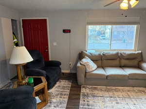 Living room with a textured ceiling, ceiling fan, and dark wood-type flooring