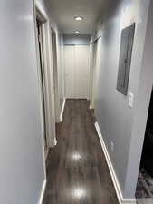 Corridor with dark hardwood / wood-style flooring and electric panel